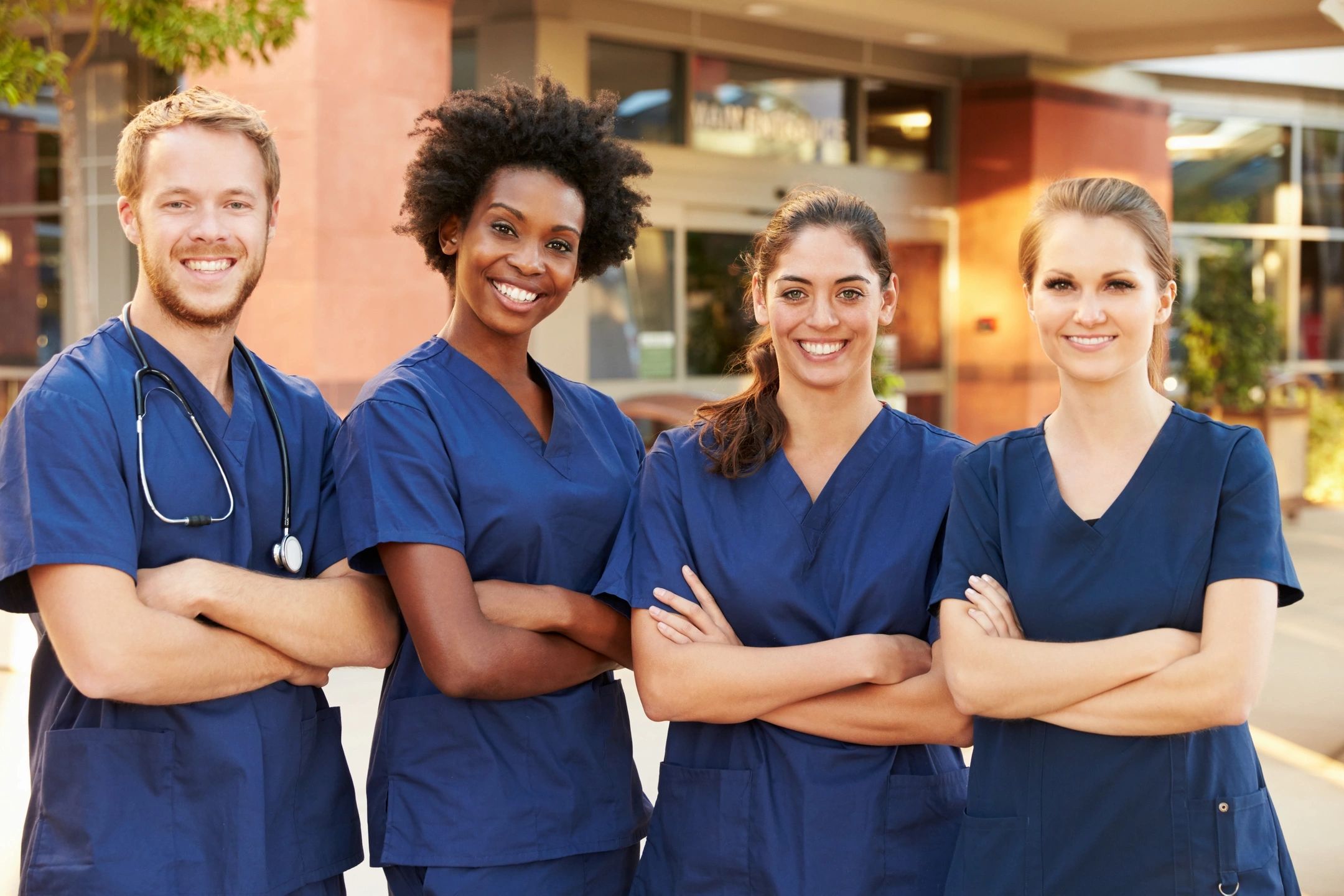 A diverse group of healthcare professionals smiling confidently in scrubs.