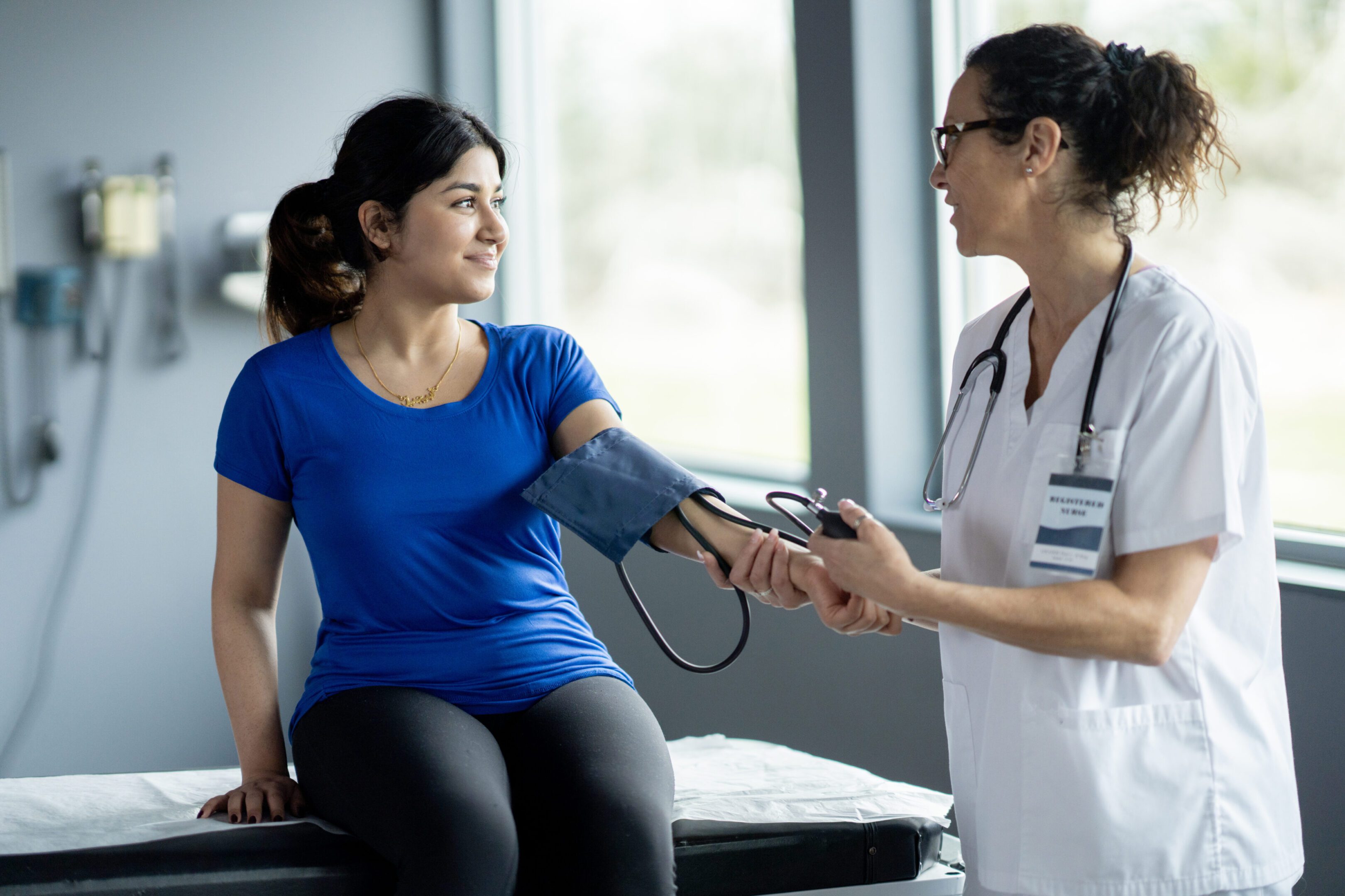 A doctor measures a patient's blood pressure in a medical setting.