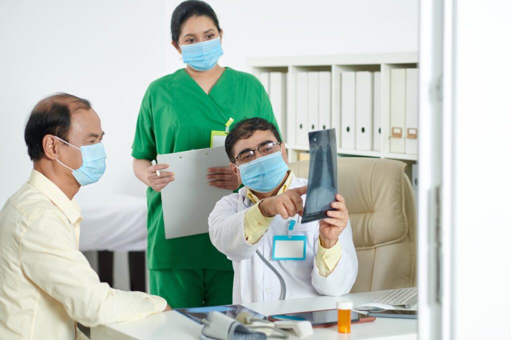 Doctor explaining X-ray to patient and nurse.