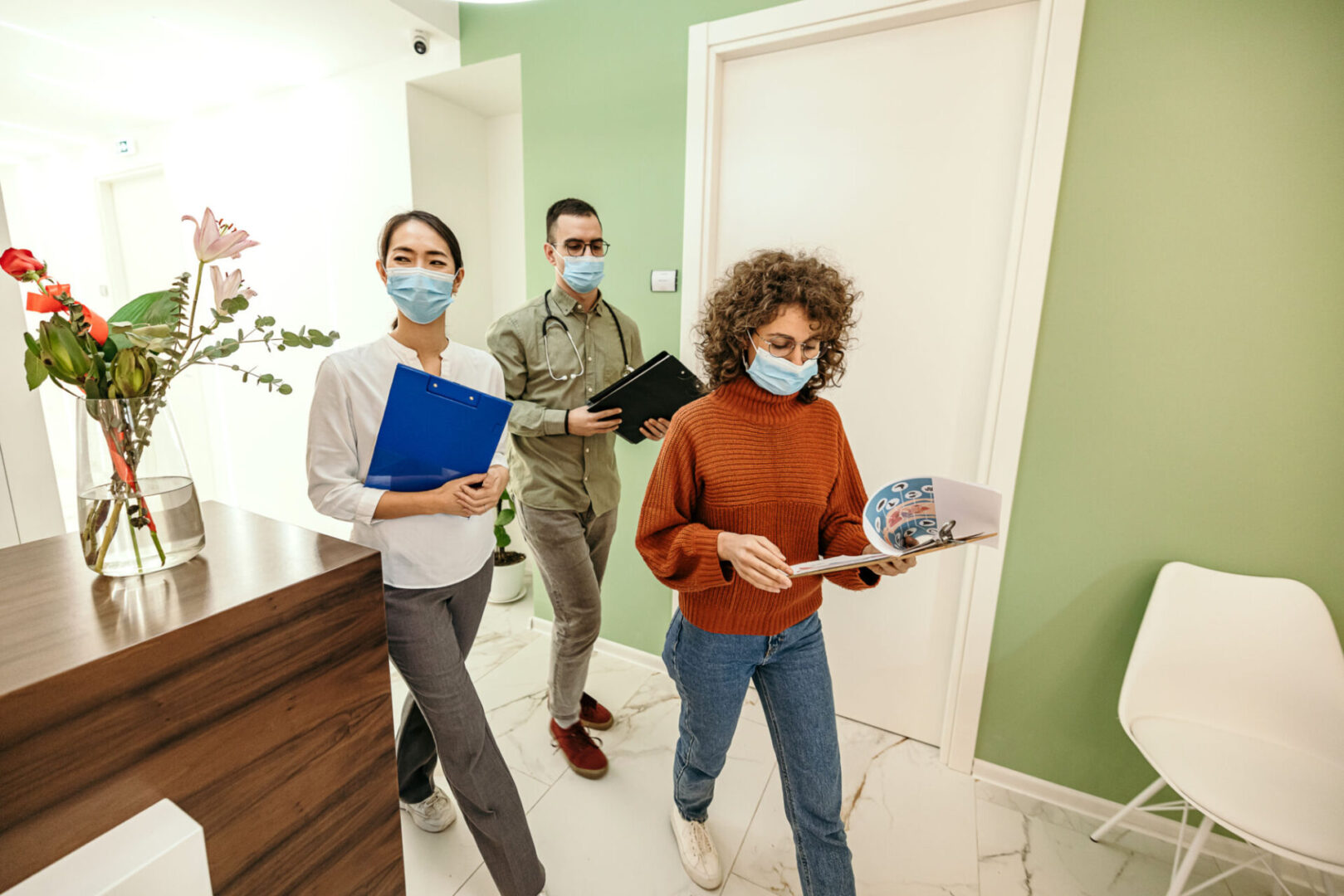 People wearing masks walking in an office.
